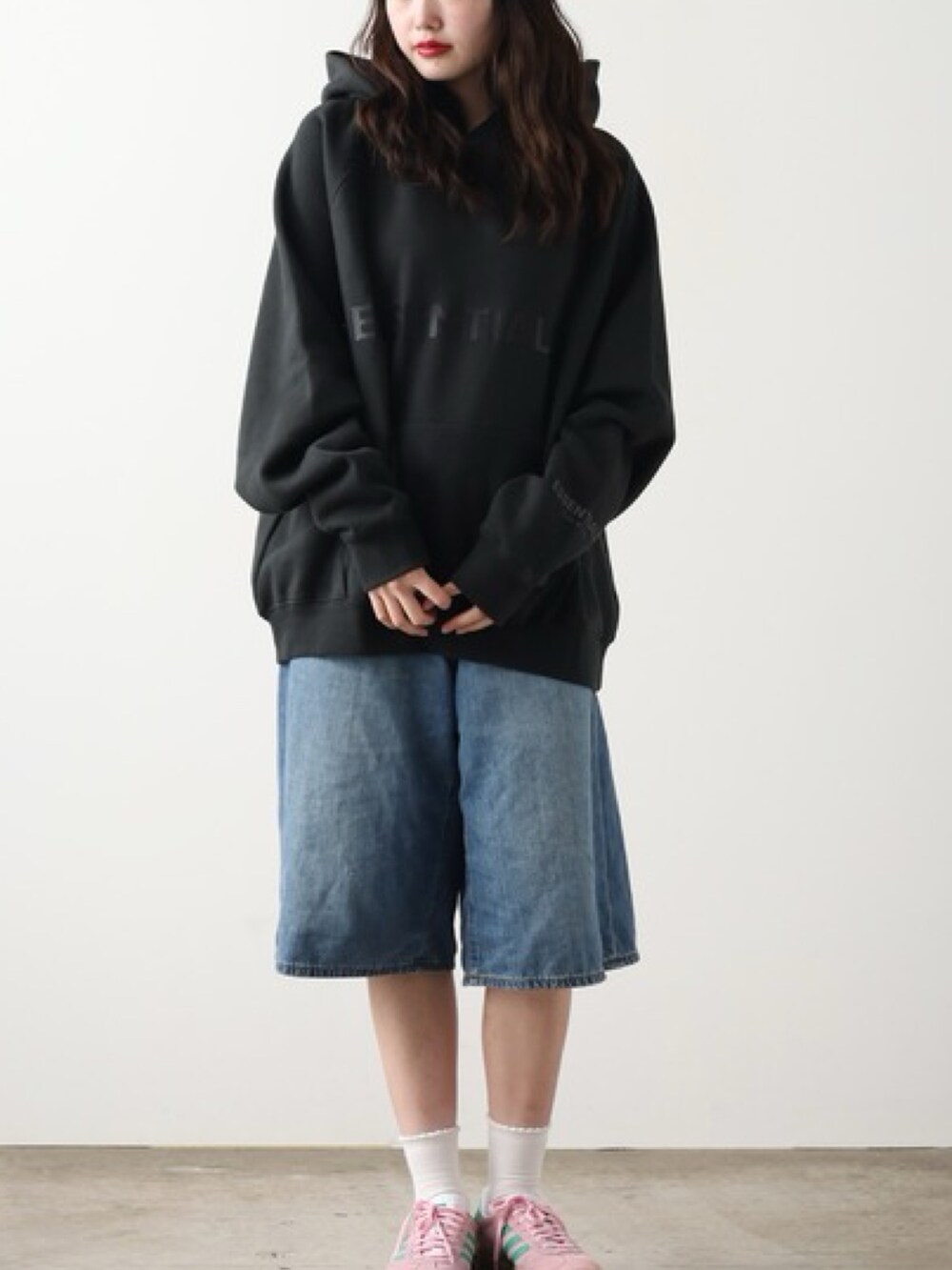 ブラック系のパーカー、ブルー系のデニムパンツ、ピンク系のスニーカーを着用したレディースの秋コーディネートの2枚目の写真