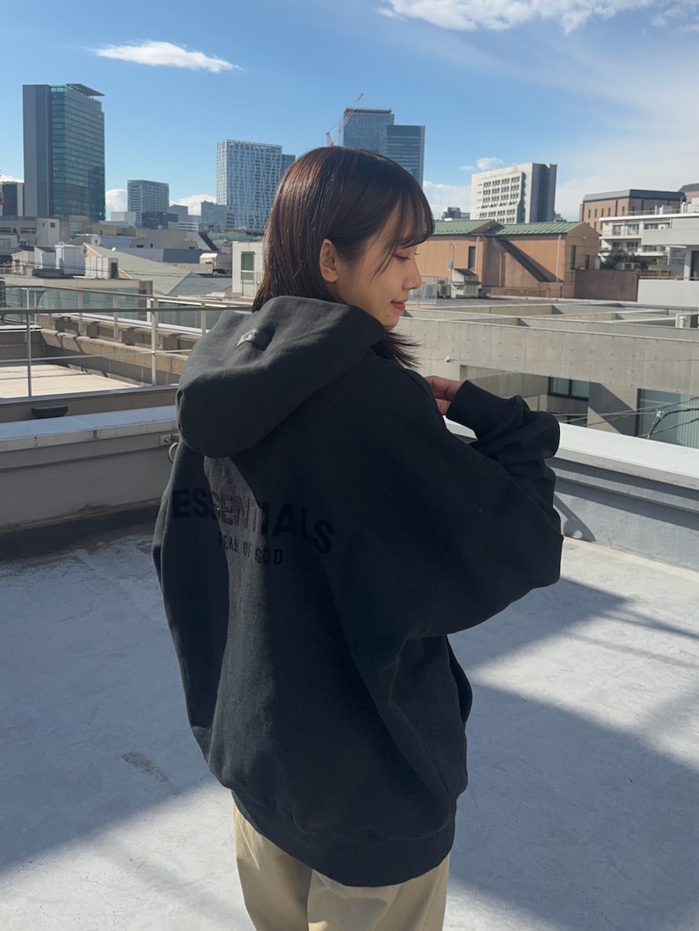 ブラック系のパーカー、ベージュ系のチノパンツ、ブラック系のスニーカーを着用したレディースの冬コーディネートの3枚目の写真