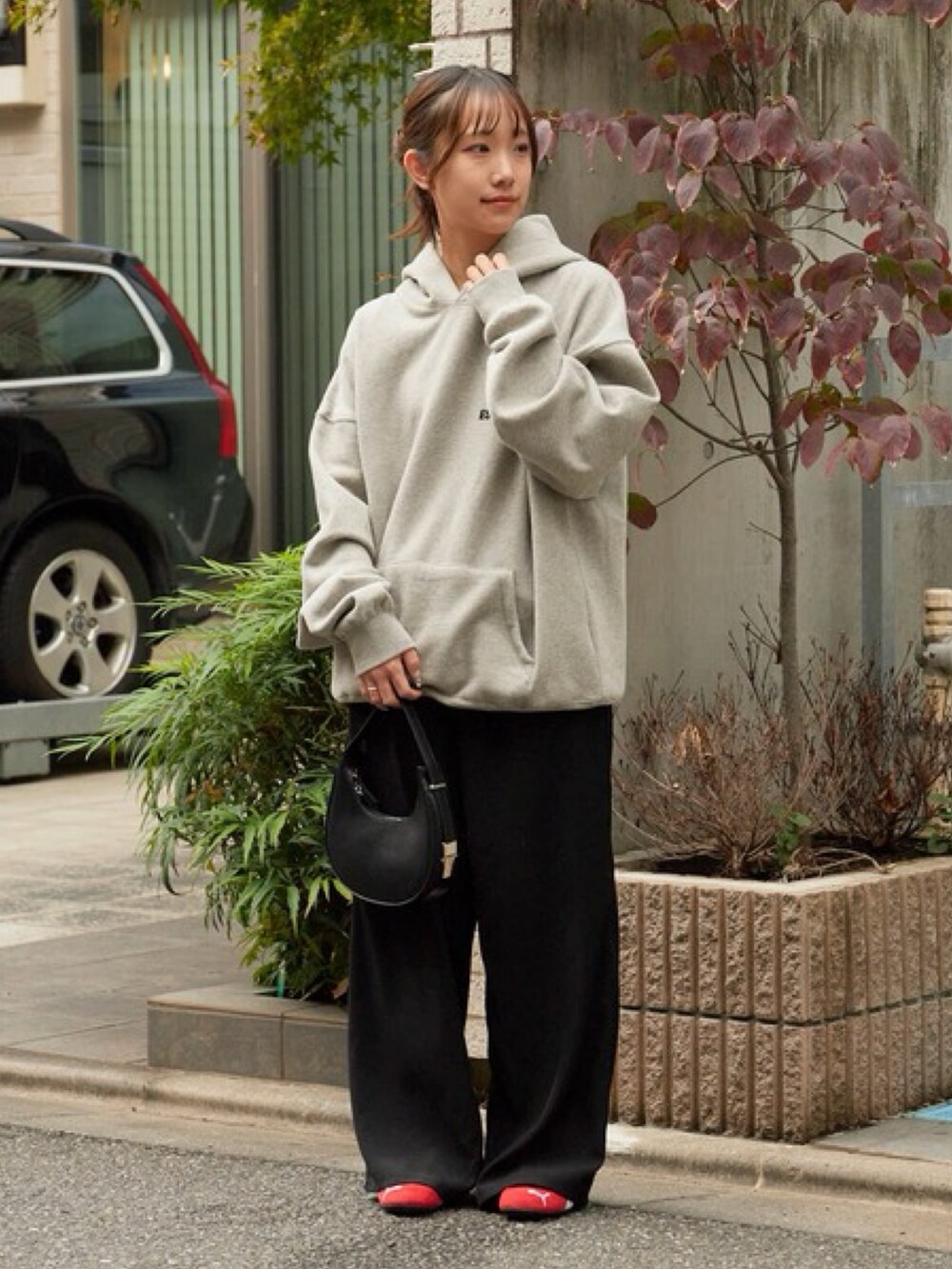 グレー系のパーカー、ブラック系のスラックス、レッド系のスニーカーを着用したレディースの秋コーディネートの6枚目の写真