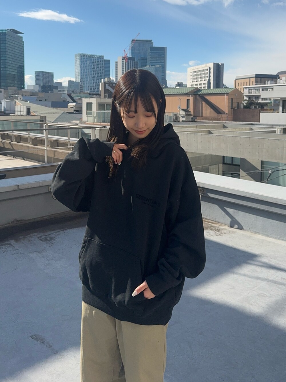 ブラック系のパーカー、ベージュ系のチノパンツ、ブラック系のスニーカーを着用したレディースの冬コーディネートの4枚目の写真