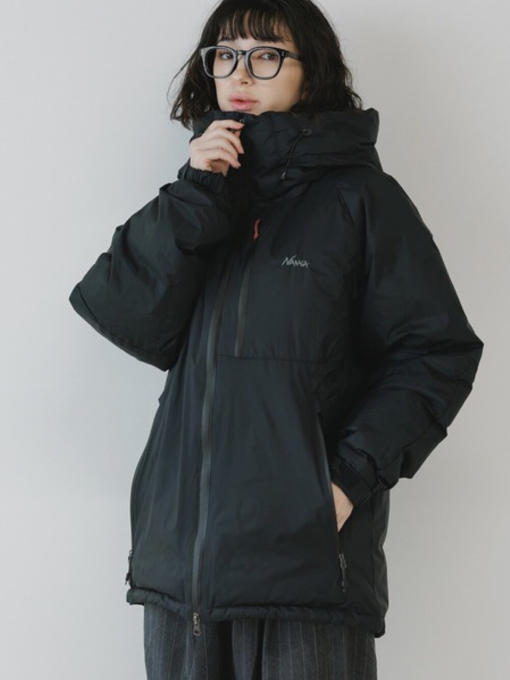 ブラック系のスラックス、ブラック系のダウンジャケット/コート、ブラック系のメガネを着用したレディースの秋コーディネートの2枚目の写真