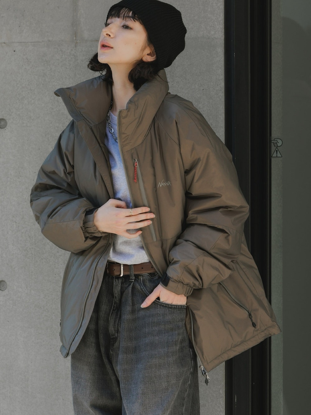 グレー系のダウンジャケット/コート、ブルー系のデニムパンツ、ブラック系のスニーカーを着用したレディースの秋コーディネートの2枚目の写真