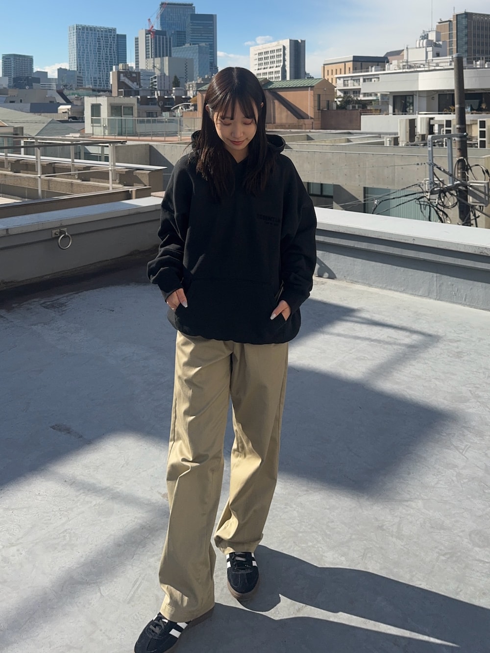 ブラック系のパーカー、ベージュ系のチノパンツ、ブラック系のスニーカーを着用したレディースの冬コーディネートの5枚目の写真
