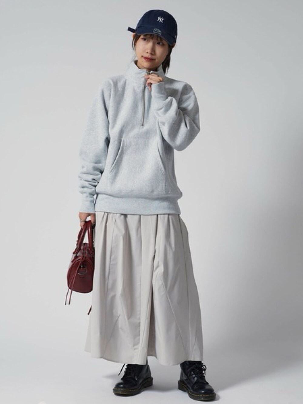 グレー系のスウェット、ホワイト系のスカート、レッド系のショルダーバッグを着用したレディースの秋コーディネートの2枚目の写真