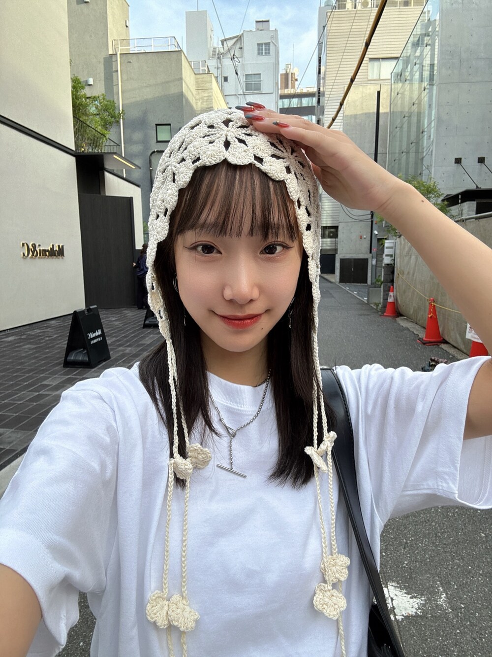 ホワイト系のTシャツ/カットソー、ブラック系のスカート、ブラック系のショルダーバッグを着用したレディースの夏コーディネートの2枚目の写真