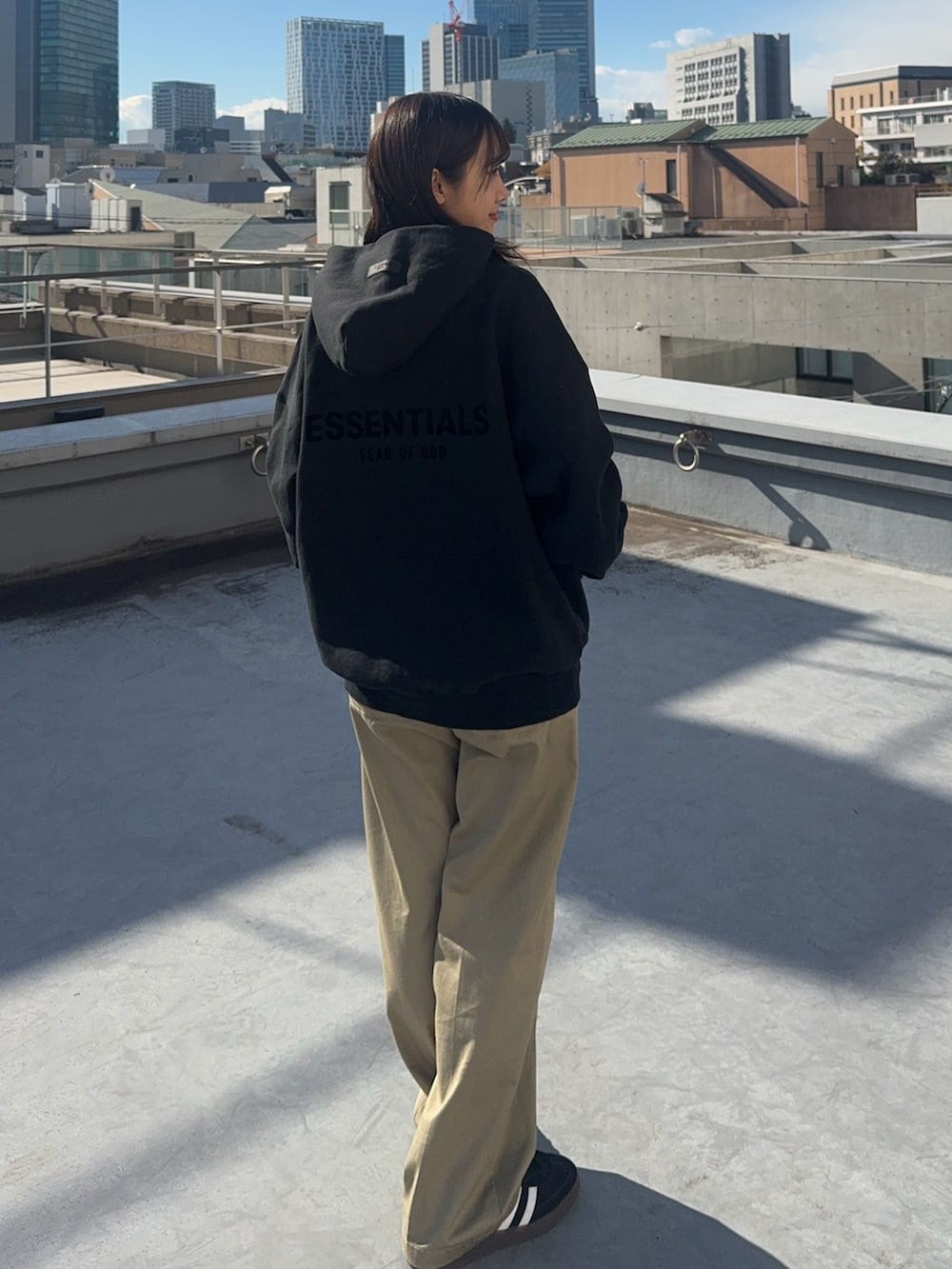 ブラック系のパーカー、ベージュ系のチノパンツ、ブラック系のスニーカーを着用したレディースの冬コーディネートの2枚目の写真