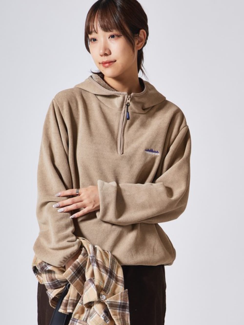 ベージュ系のパーカー、ブラウン系のチノパンツを着用したレディースの冬コーディネートの2枚目の写真