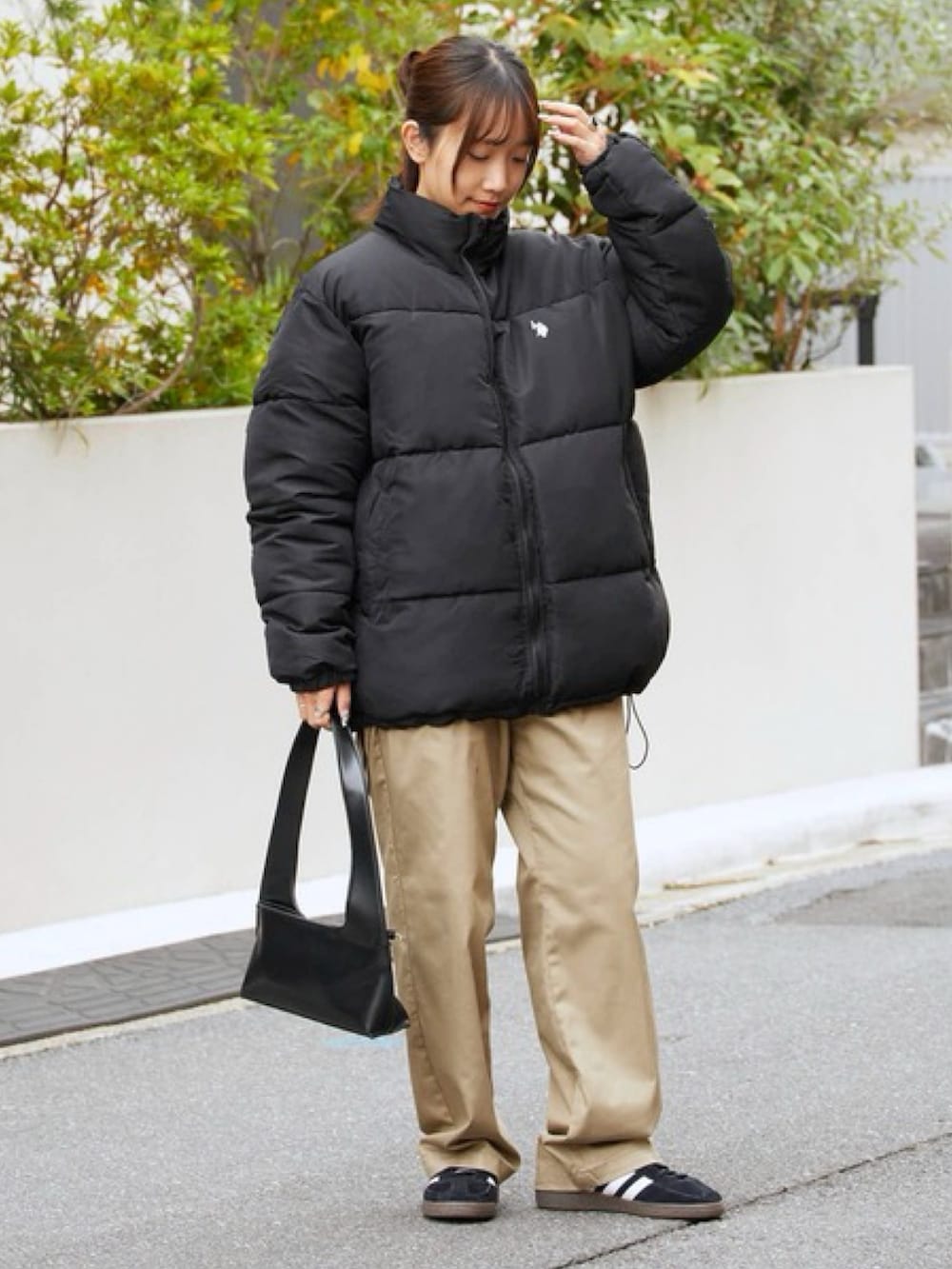 ブラック系のダウンジャケット/コート、ベージュ系のチノパンツを着用したレディースの秋コーディネートの2枚目の写真