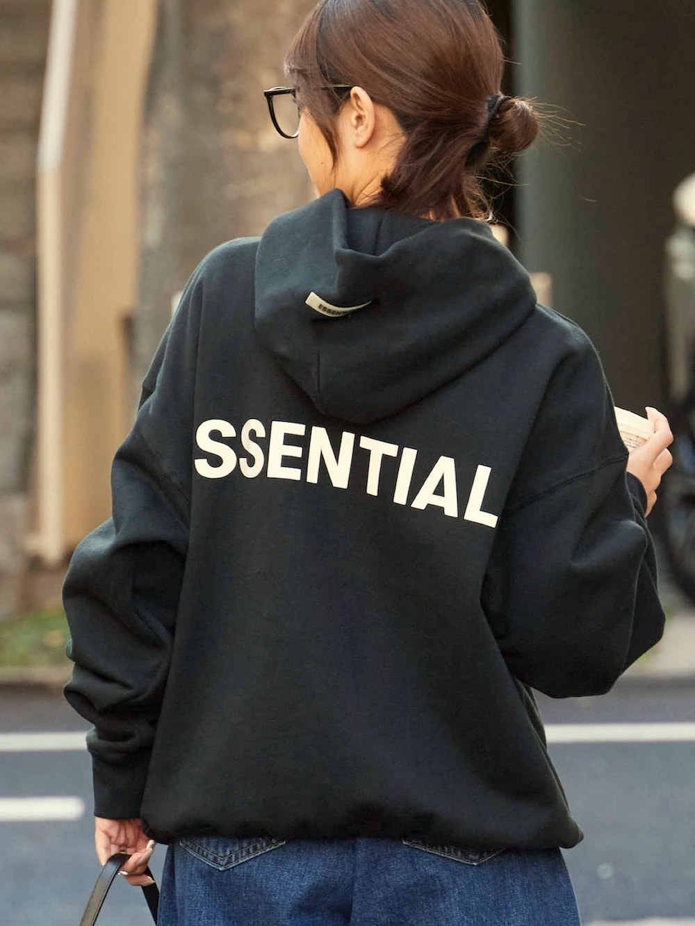 ブラック系のパーカー、ブルー系のデニムパンツを着用したレディースの春コーディネートの3枚目の写真