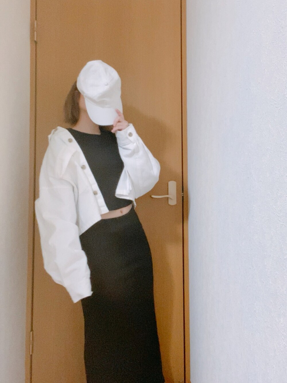 ブラック系のTシャツ/カットソー、ブラック系のスカート、ホワイト系のキャップを着用したレディースの春コーディネートの2枚目の写真