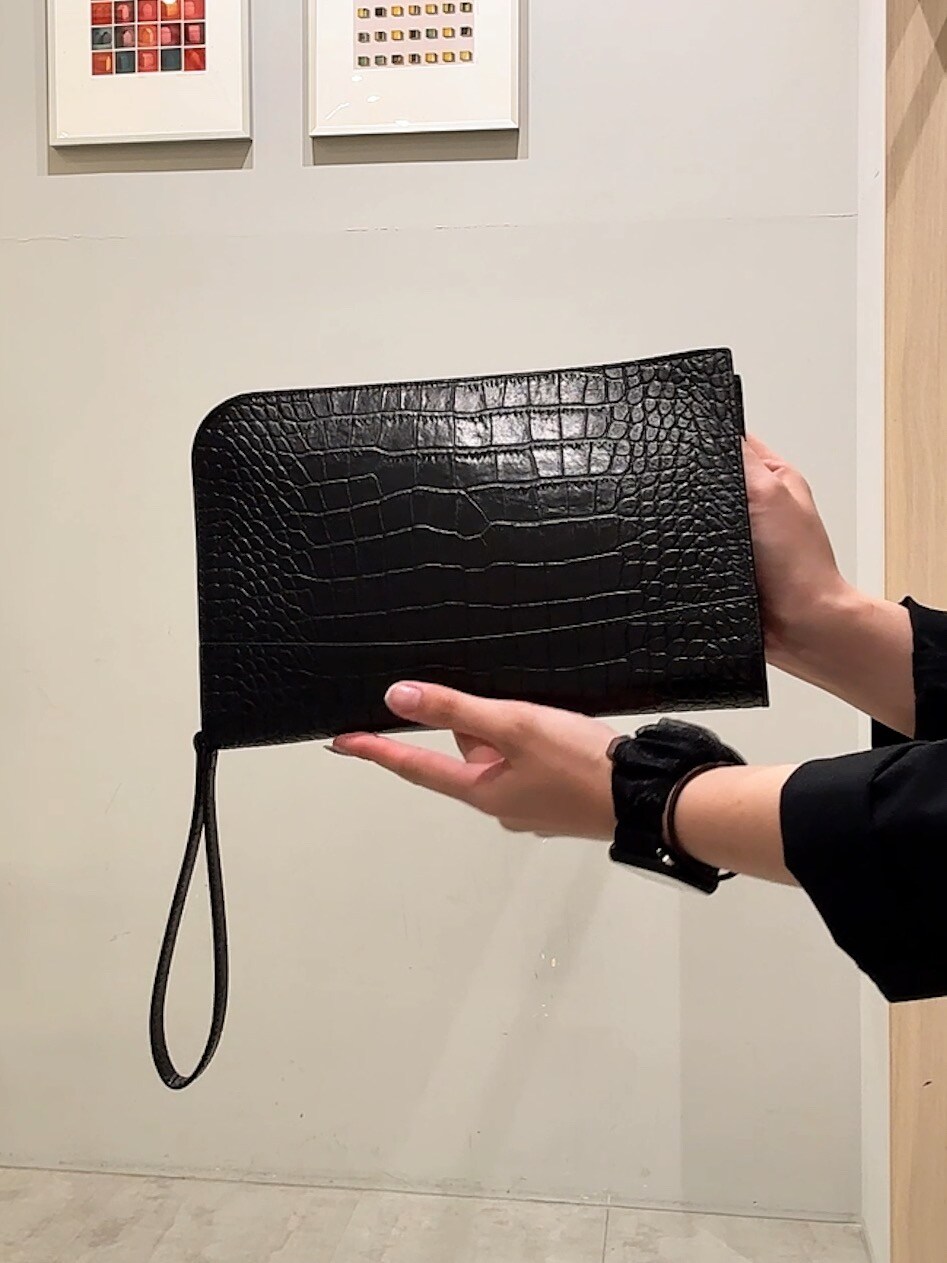 ブラウン系のポロシャツ、ブラック系のテーラードジャケット、ブラック系のクラッチバッグを着用したレディースの夏コーディネートの6枚目の写真