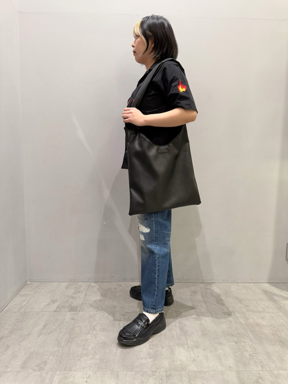 ブルー系のデニムパンツ、ブラック系のシャツ/ブラウス、ブラック系のその他シューズを着用したレディースの春コーディネートの2枚目の写真