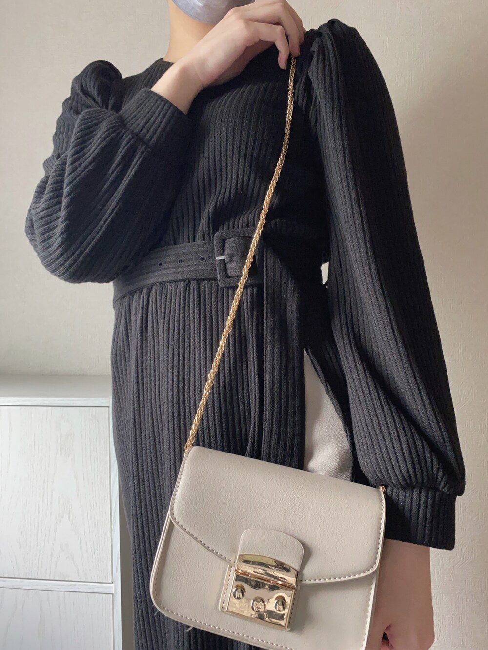 ホワイト系のショルダーバッグ、ブラック系のワンピース、ベージュ系のスラックスを着用したレディースの春コーディネートの2枚目の写真