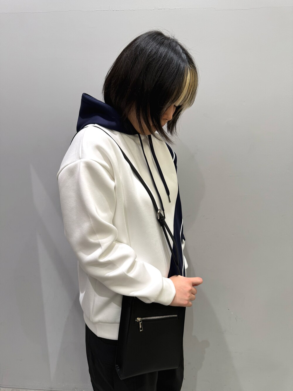 ブラック系のカーゴパンツ、ホワイト系のパーカー、ブラック系のショルダーバッグを着用したレディースの春コーディネートの2枚目の写真