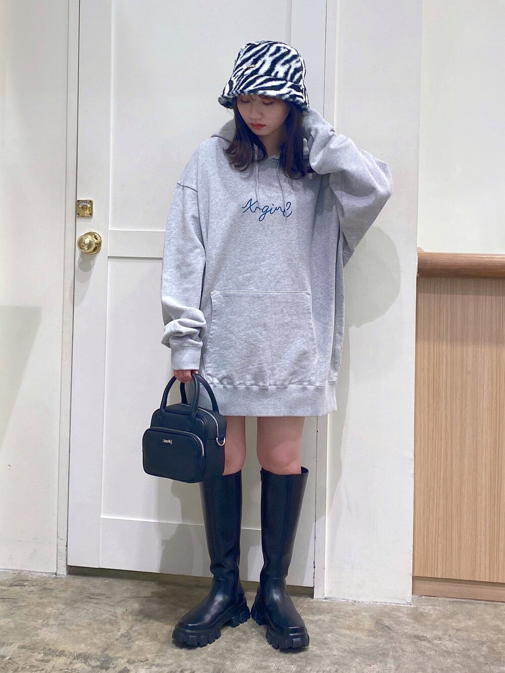 グレー系のパーカー、ブラック系のスカート、ブラック系のブーツを着用したレディースの秋コーディネートの3枚目の写真