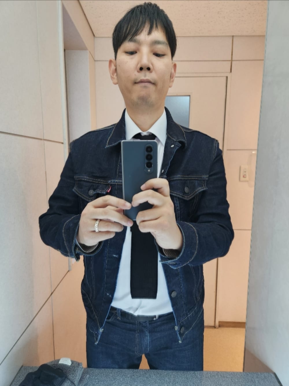 ブルー系のデニムジャケット、ホワイト系のビジネスシャツ、ブラック系のネクタイを着用したメンズの冬コーディネートの3枚目の写真