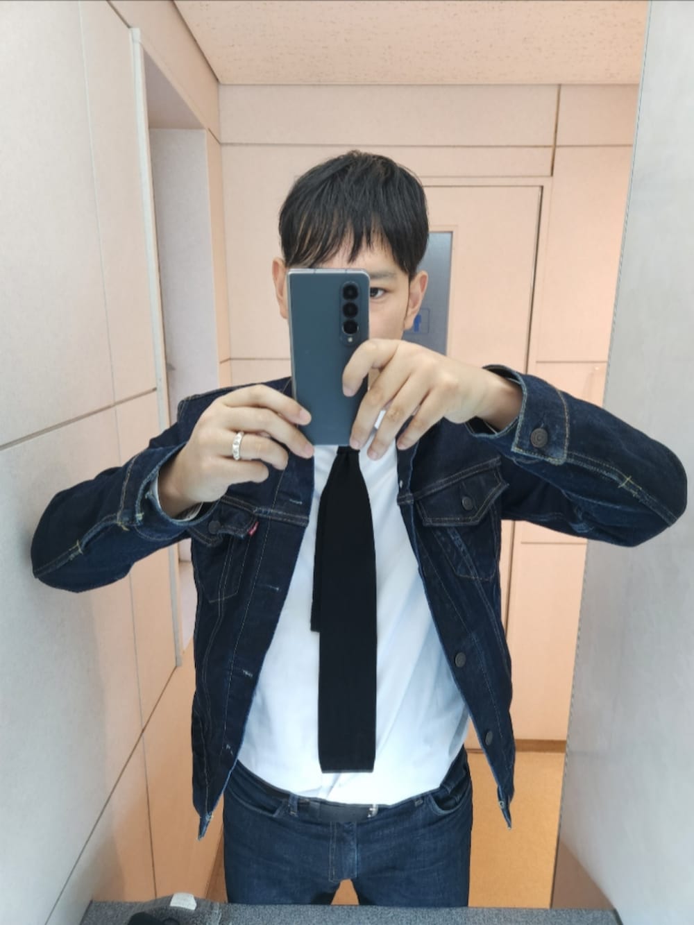 ブルー系のデニムジャケット、ホワイト系のビジネスシャツ、ブラック系のネクタイを着用したメンズの冬コーディネートの2枚目の写真