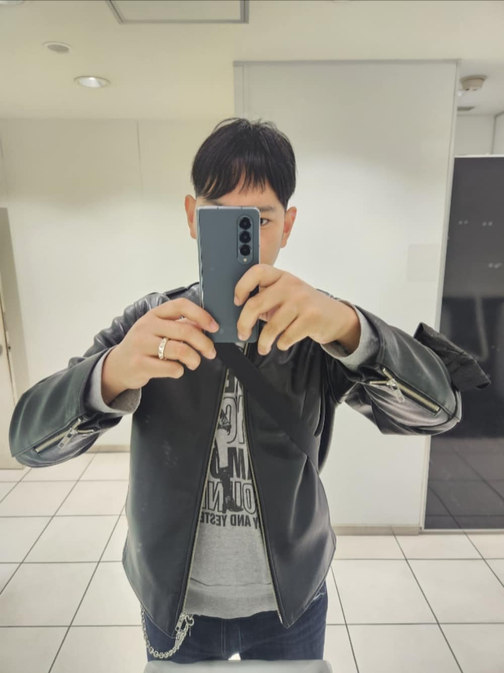 ブラック系のライダースジャケット、グレー系のスウェット、ブルー系のデニムパンツを着用したメンズの秋コーディネートの2枚目の写真