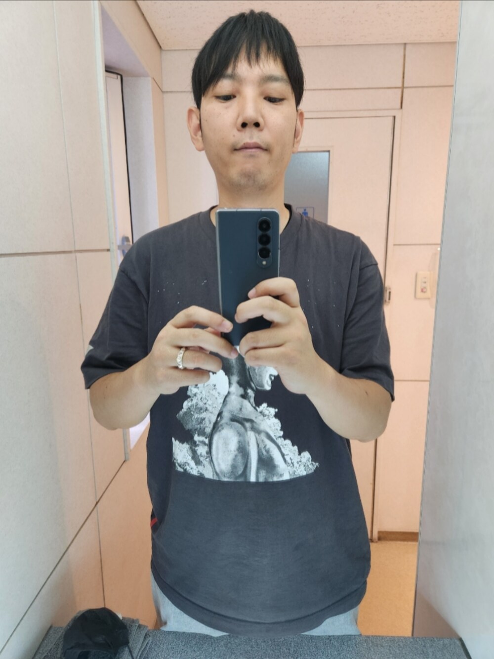 グレー系のTシャツ/カットソー、グレー系のデニムパンツ、ブラック系のスニーカーを着用したメンズの秋コーディネートの3枚目の写真