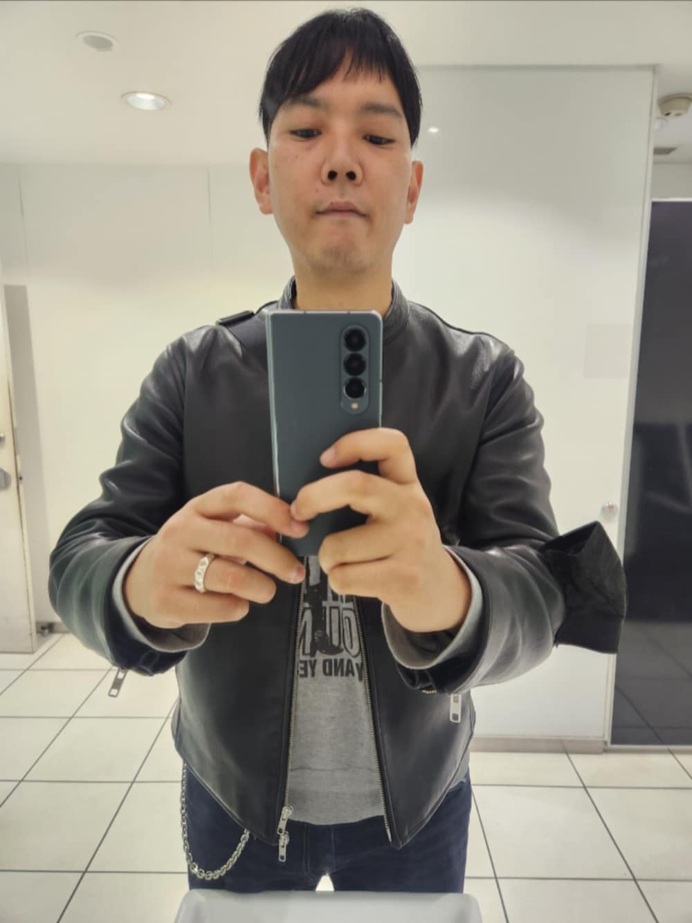 ブラック系のライダースジャケット、グレー系のスウェット、ブルー系のデニムパンツを着用したメンズの秋コーディネートの3枚目の写真