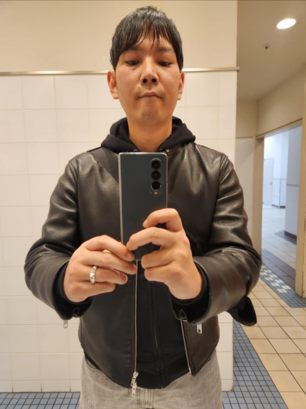 ブラック系のライダースジャケット、ブラック系のパーカー、グレー系のデニムパンツを着用したメンズの冬コーディネートの2枚目の写真