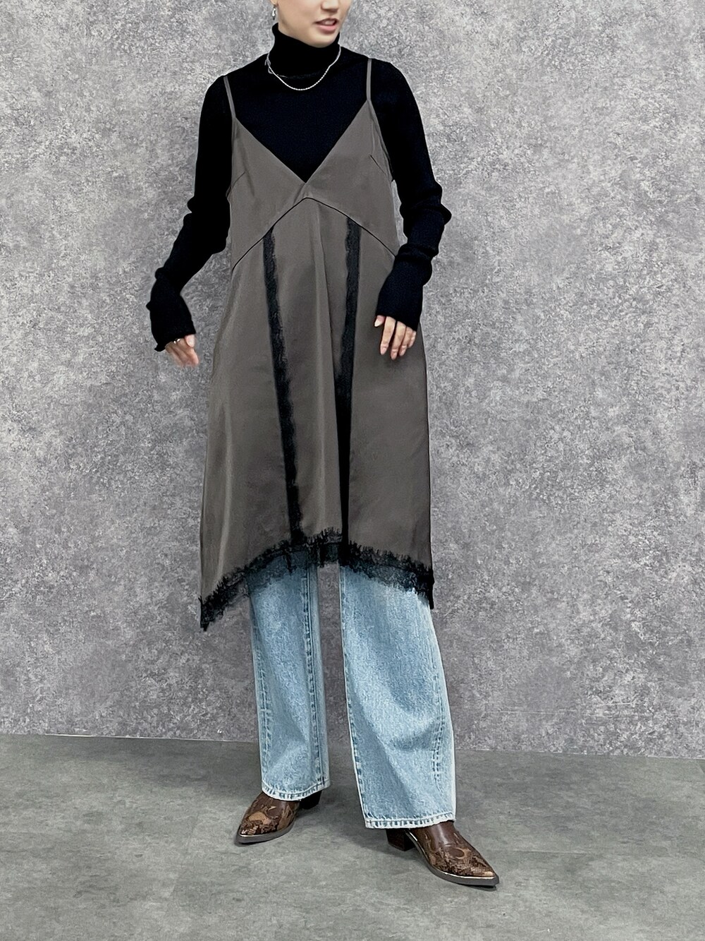 ブルー系のデニムパンツ、ブラック系のニット/セーター、ブラウン系のワンピースを着用したレディースの秋コーディネートの4枚目の写真