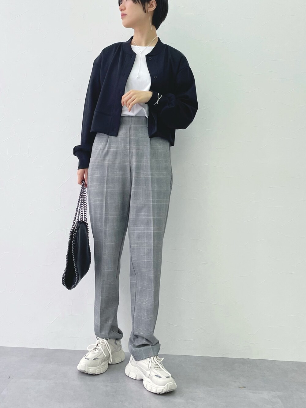 グレー系のパンツ、ブラック系のワンピース、ホワイト系のTシャツ/カットソーを着用したレディースの春コーディネートの2枚目の写真