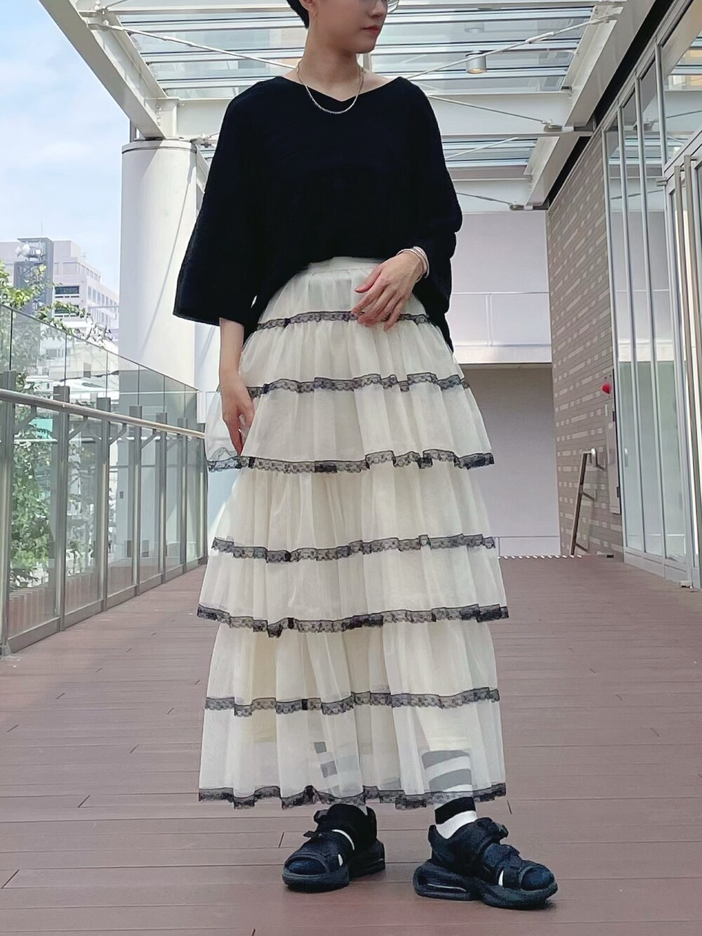 ホワイト系のスカート、ホワイト系のスカート、ブラック系のチュニックを着用したレディースの秋コーディネートの2枚目の写真