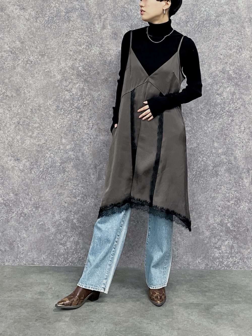 ブルー系のデニムパンツ、ブラック系のニット/セーター、ブラウン系のワンピースを着用したレディースの秋コーディネートの3枚目の写真