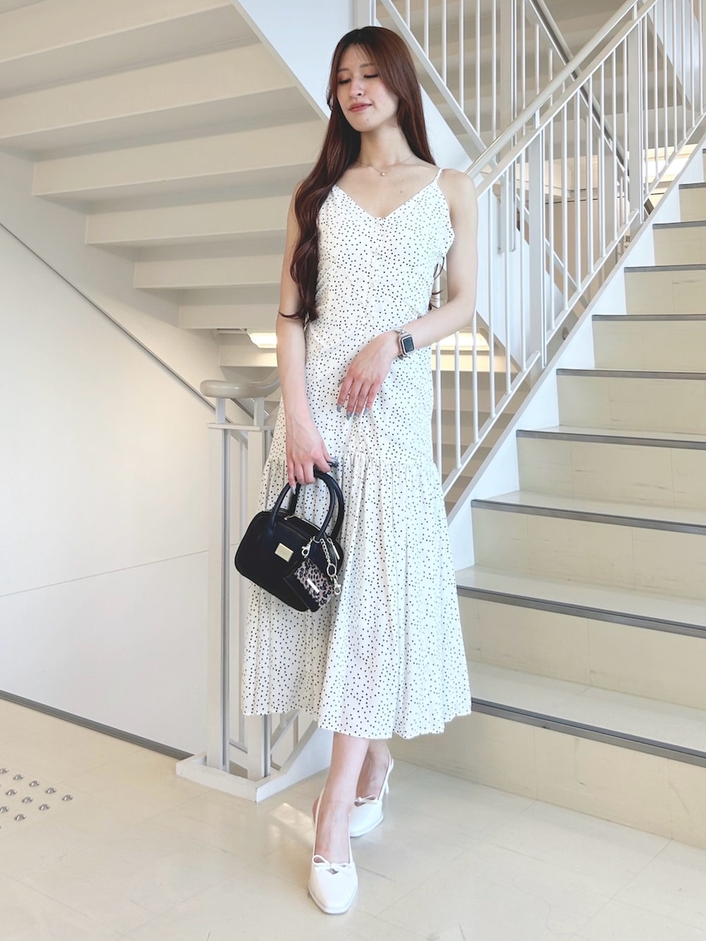 ホワイト系のパンプス、ブラック系のハンドバッグ、ホワイト系のワンピースを着用したレディースの秋コーディネートの3枚目の写真