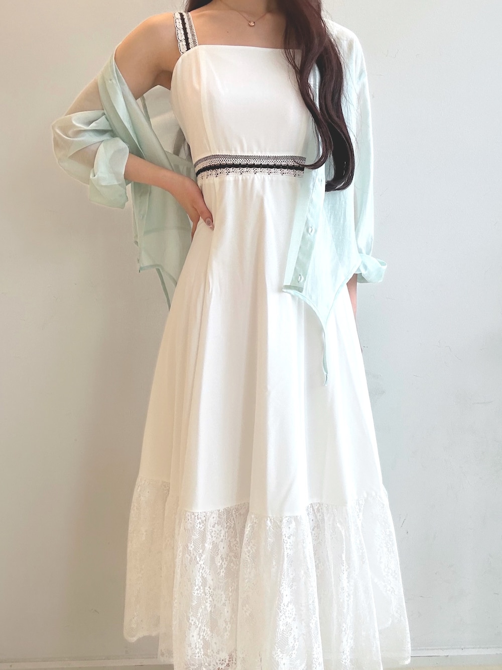 グリーン系のハンドバッグ、ホワイト系のワンピース、ブラウン系のサンダルを着用したレディースの夏コーディネートの5枚目の写真