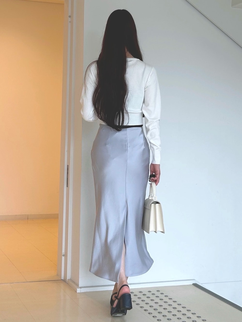 ホワイト系のハンドバッグ、ブルー系のパンプス、ホワイト系のカーディガン/ボレロを着用したレディースの夏コーディネートの4枚目の写真