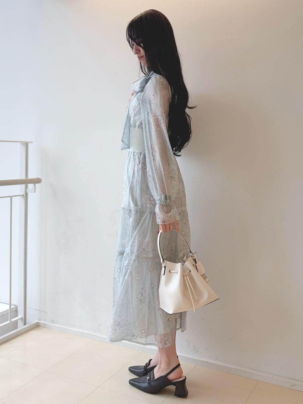 グリーン系のワンピース、ホワイト系のショルダーバッグ、ブラウン系のパンプスを着用したレディースの冬コーディネートの3枚目の写真