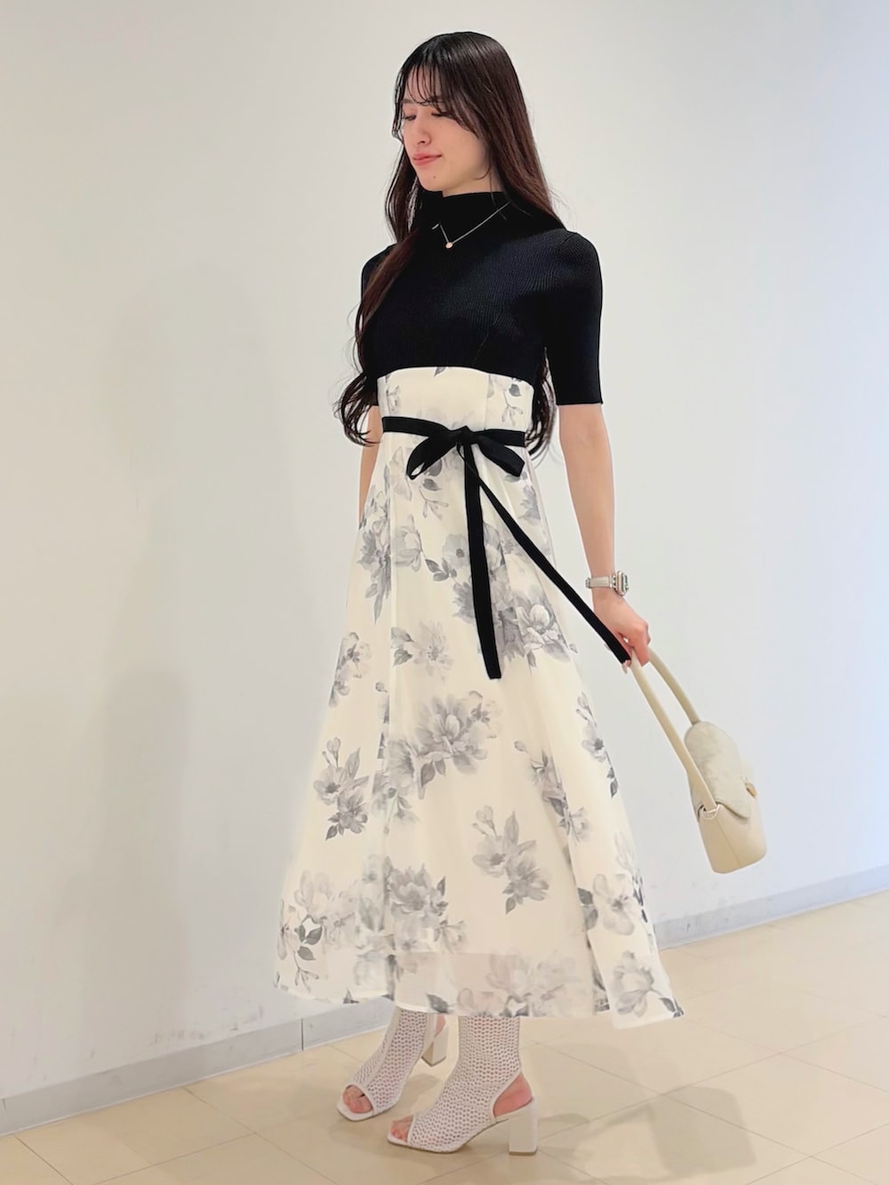 ブラック系のワンピース、パープル系のトレンチコート、ホワイト系のハンドバッグを着用したレディースの春コーディネートの5枚目の写真