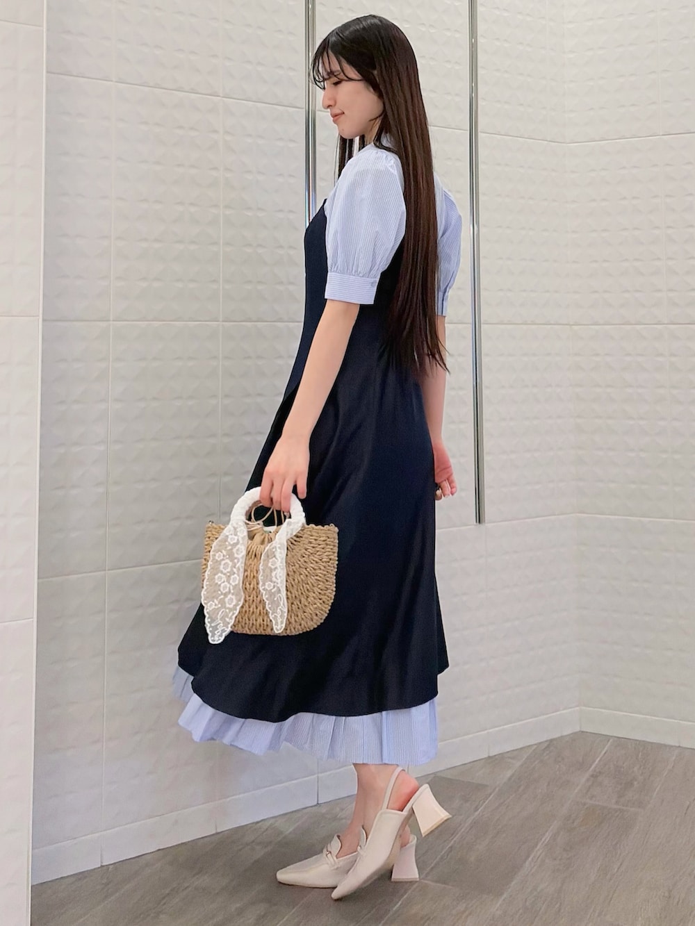 ブルー系のワンピース、ホワイト系のパンプス、ベージュ系のハンドバッグを着用したレディースの春コーディネートの2枚目の写真