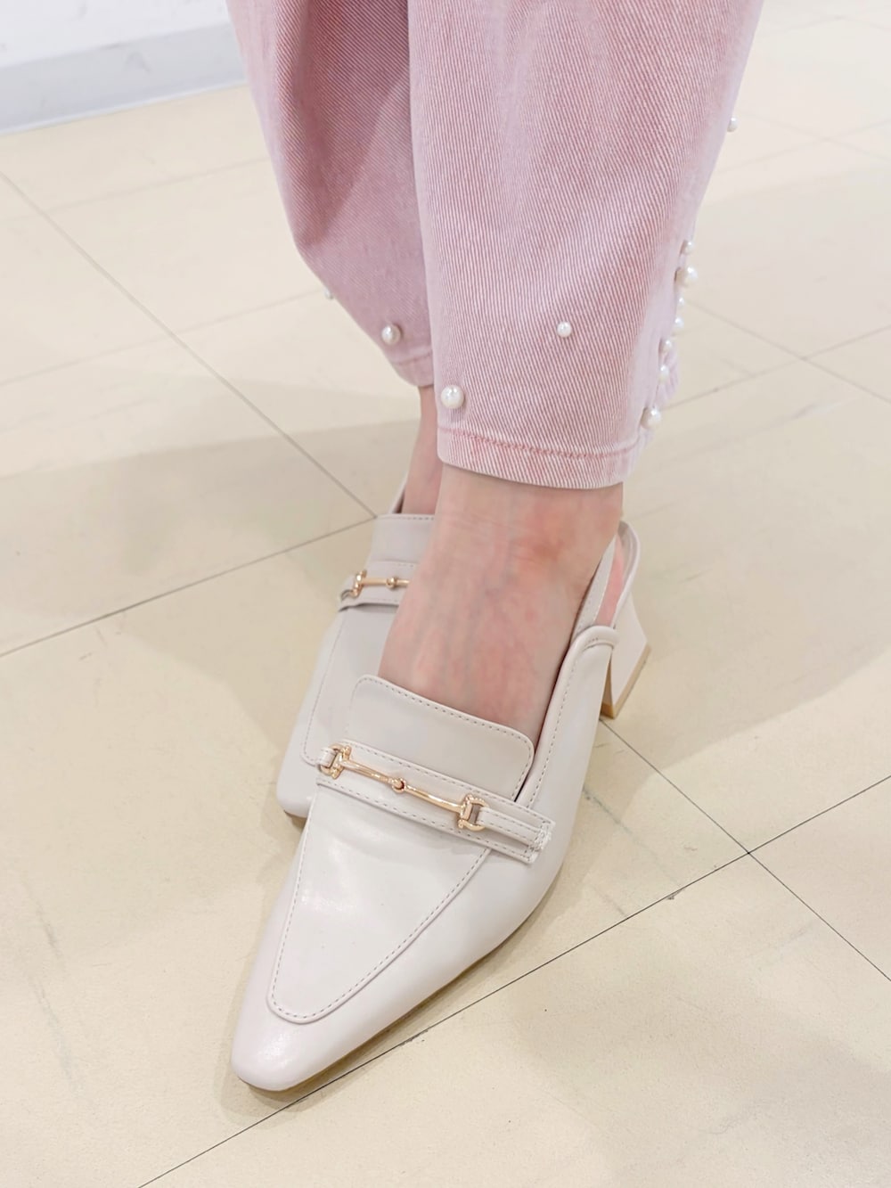 グレー系のワンピース、ブラック系のハンドバッグ、ホワイト系のパンプスを着用したレディースの春コーディネートの6枚目の写真