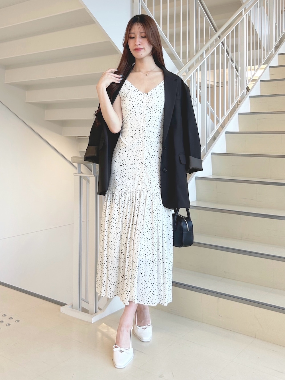 ブラック系のハンドバッグ、ホワイト系のパンプス、ブラウン系のテーラードジャケットを着用したレディースの秋コーディネートの5枚目の写真