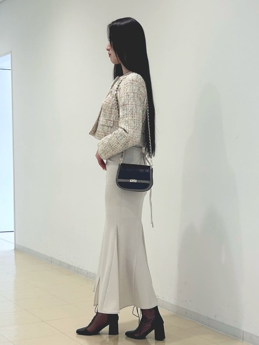 ホワイト系のスカート、ベージュ系のノーカラージャケット、ブラウン系のハンドバッグを着用したレディースの春コーディネートの2枚目の写真