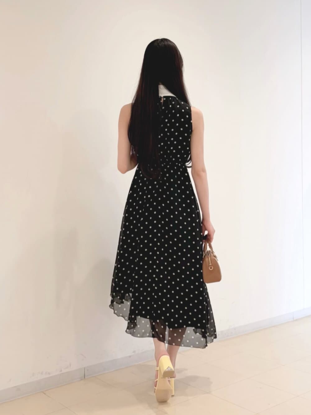 ブラック系のキャミソール、ブラウン系のハンドバッグ、ブラック系のワンピースを着用したレディースの夏コーディネートの3枚目の写真