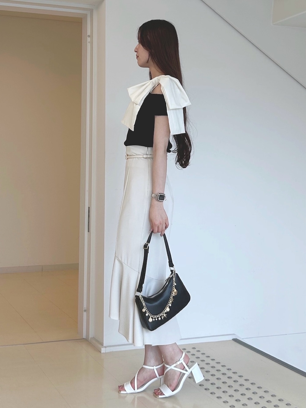 ブラック系のニット/セーター、ブラック系のハンドバッグ、ホワイト系のサンダルを着用したレディースの夏コーディネートの2枚目の写真