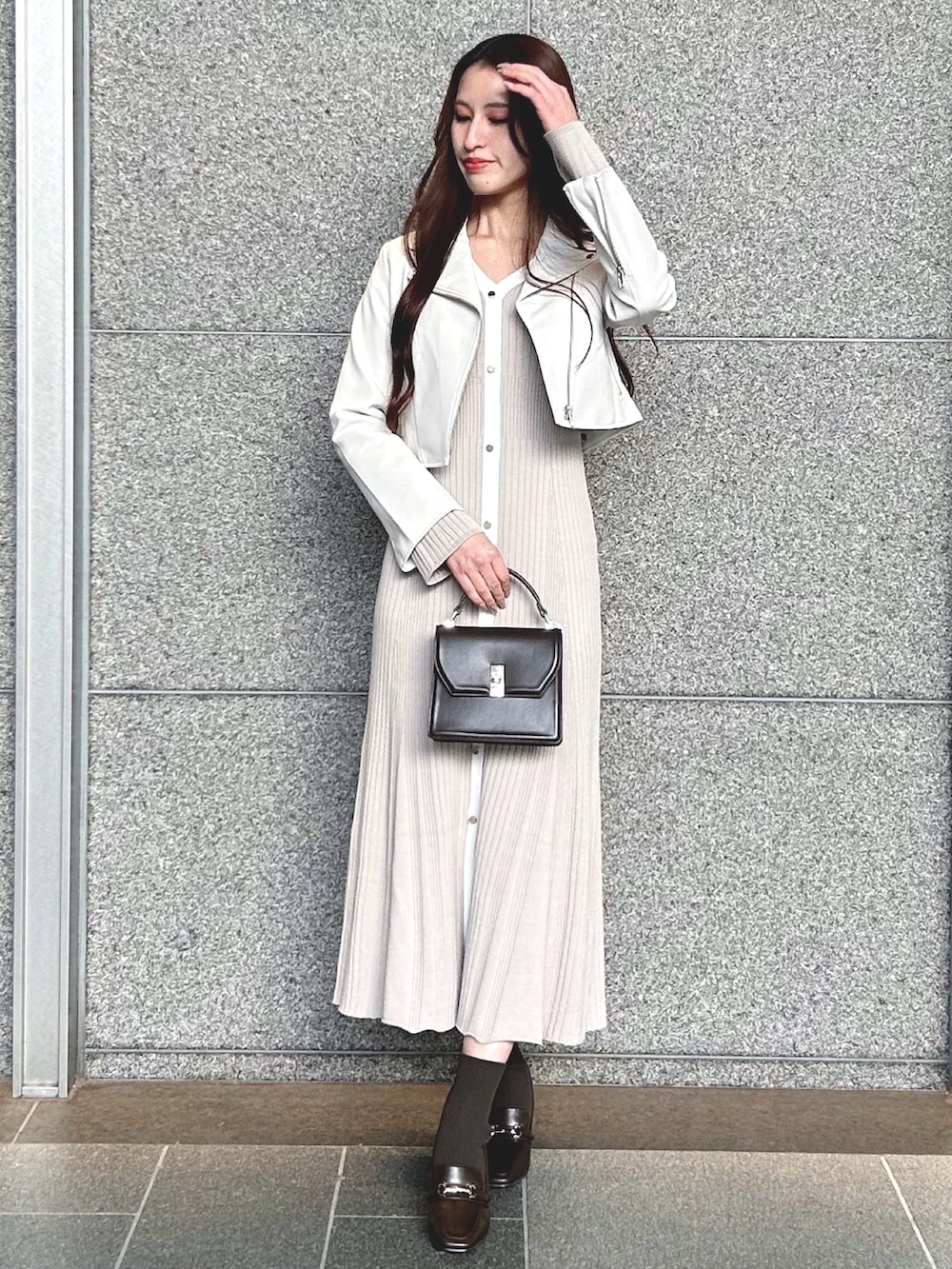 ブラウン系のハンドバッグ、ホワイト系のライダースジャケット、ピンク系のワンピースを着用したレディースの冬コーディネートの3枚目の写真