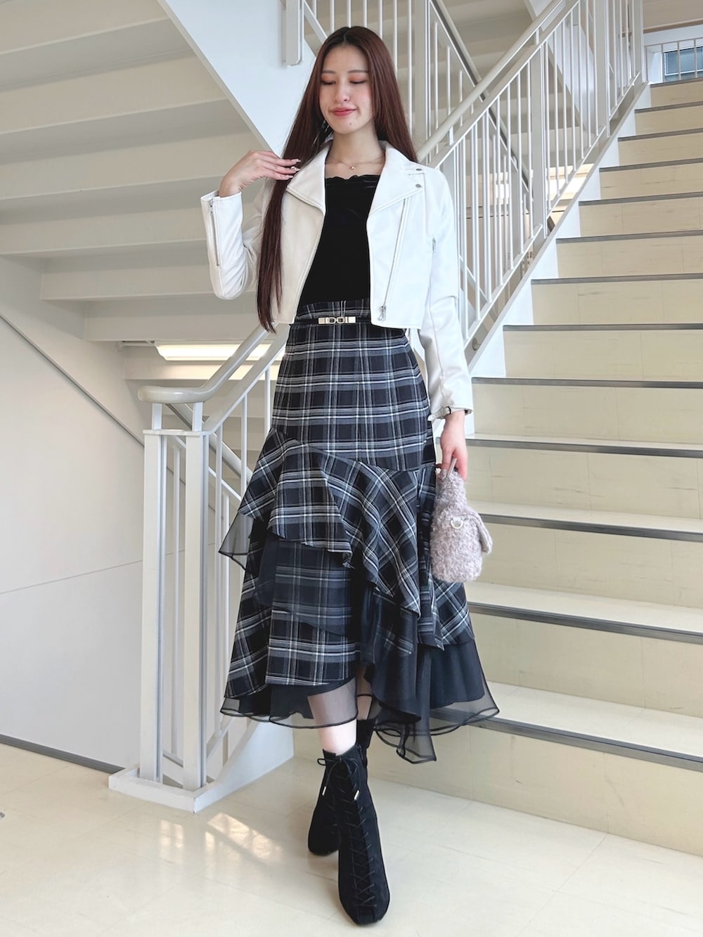 ブラック系のブーツ、ブラック系のスカート、ピンク系のハンドバッグを着用したレディースの秋コーディネートの3枚目の写真