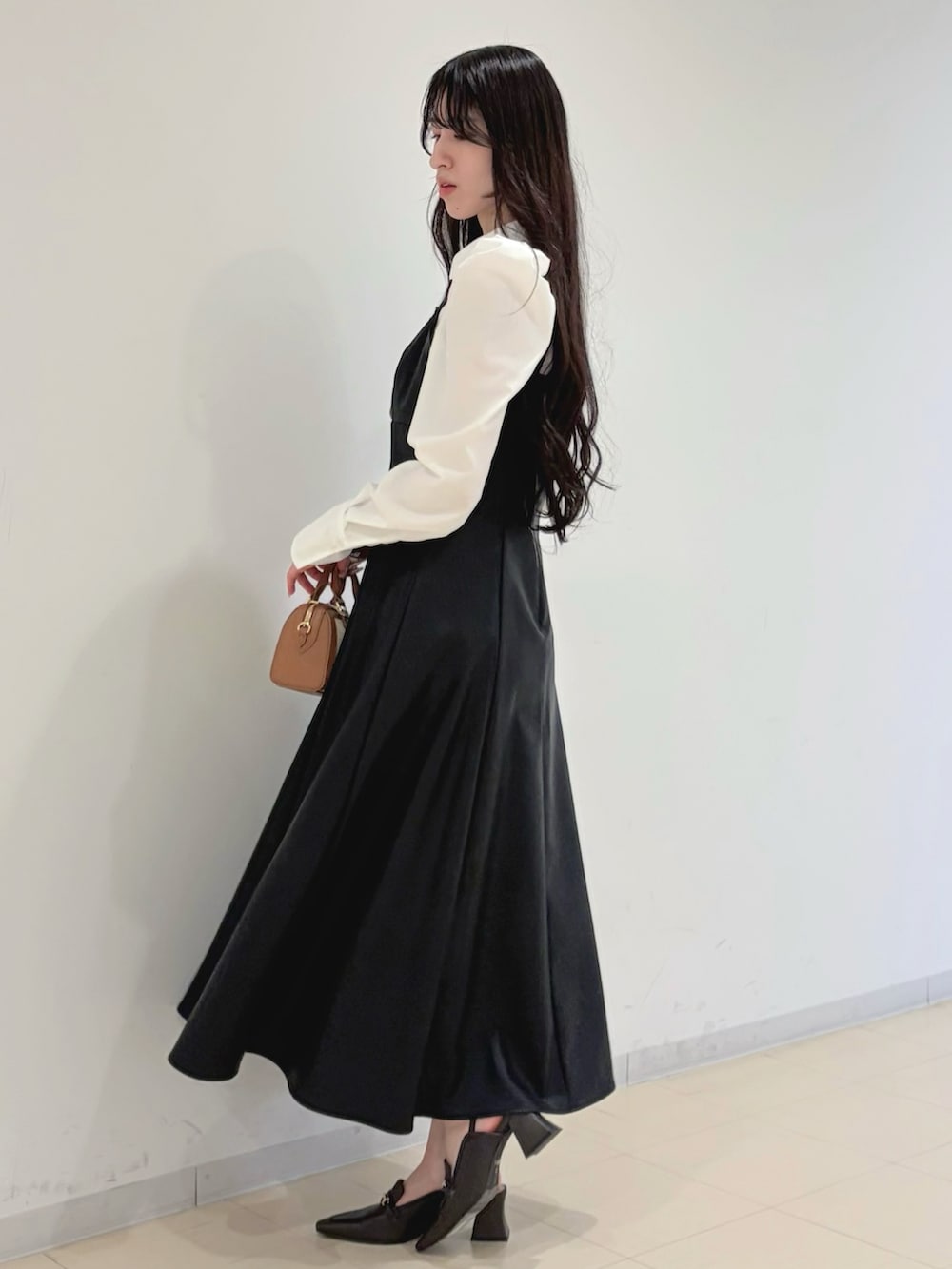 ブラック系のワンピース、ベージュ系のトレンチコート、ブラウン系のハンドバッグを着用したレディースの冬コーディネートの4枚目の写真