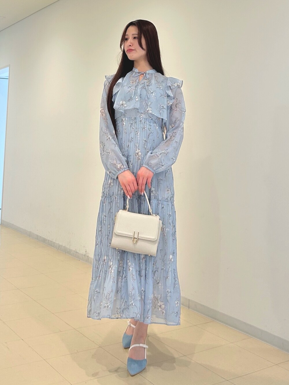 ブルー系のワンピース、ホワイト系のパンプス、ホワイト系のハンドバッグを着用したレディースの春コーディネートの3枚目の写真