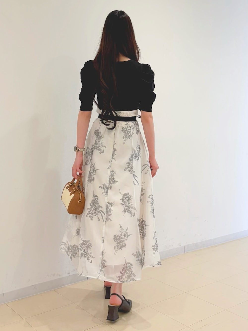 ブラック系のワンピース、ブラウン系のハンドバッグ、ブラウン系のパンプスを着用したレディースの春コーディネートの3枚目の写真