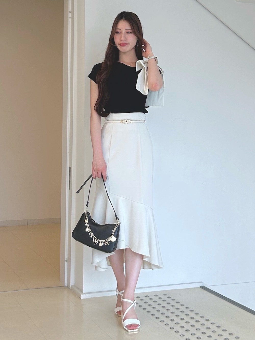 ブラック系のニット/セーター、ブラック系のハンドバッグ、ホワイト系のサンダルを着用したレディースの夏コーディネートの3枚目の写真