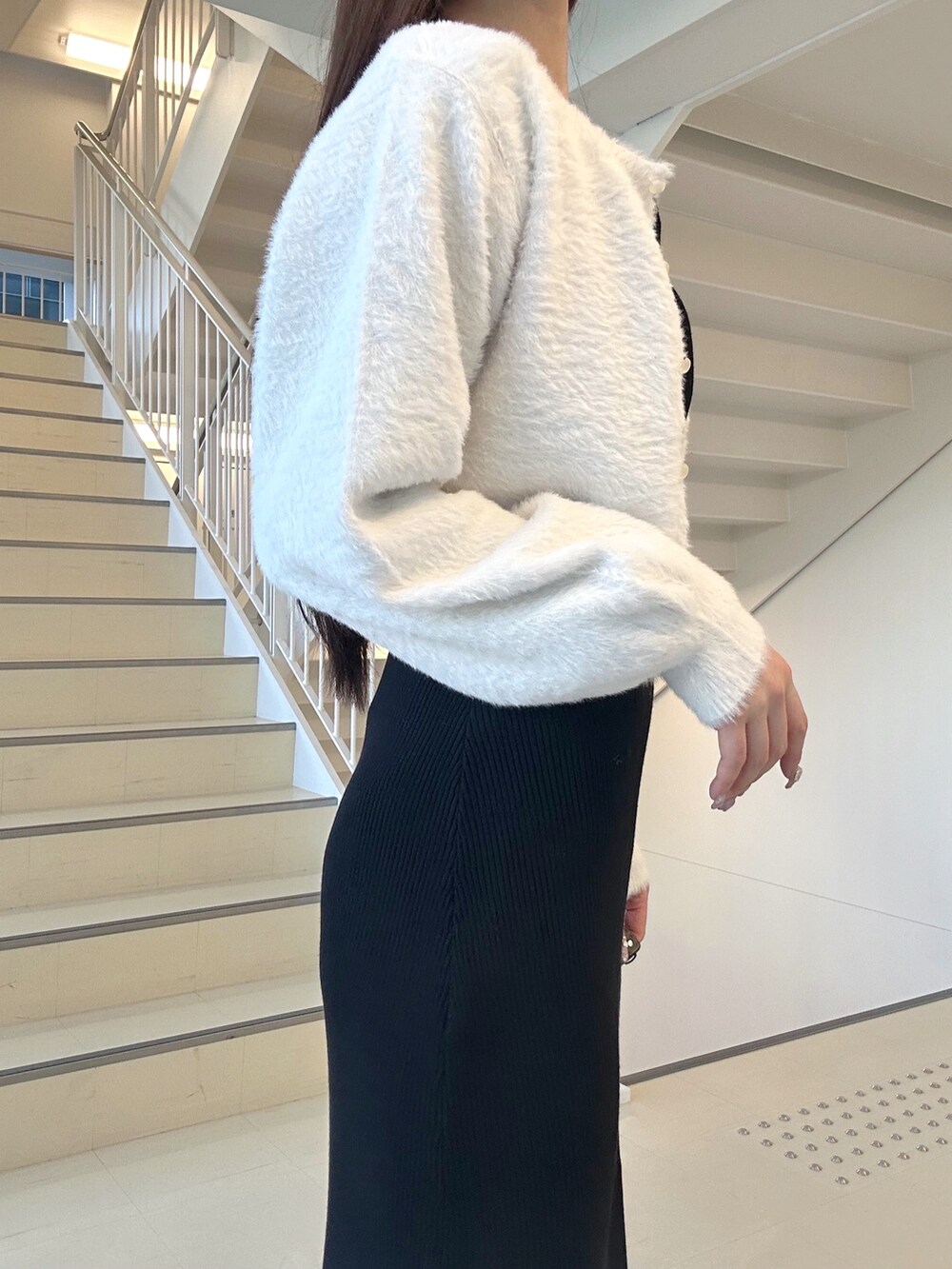 ブラック系のワンピース、ブラック系のキャミソール、ホワイト系のカーディガン/ボレロを着用したレディースの冬コーディネートの5枚目の写真