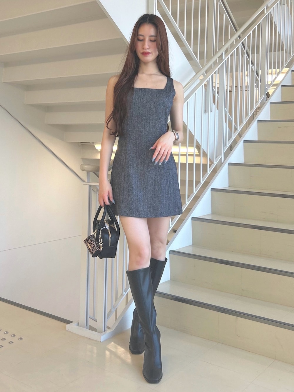 グレー系のワンピース、ブラック系のブーツ、ブラック系のハンドバッグを着用したレディースの夏コーディネートの3枚目の写真