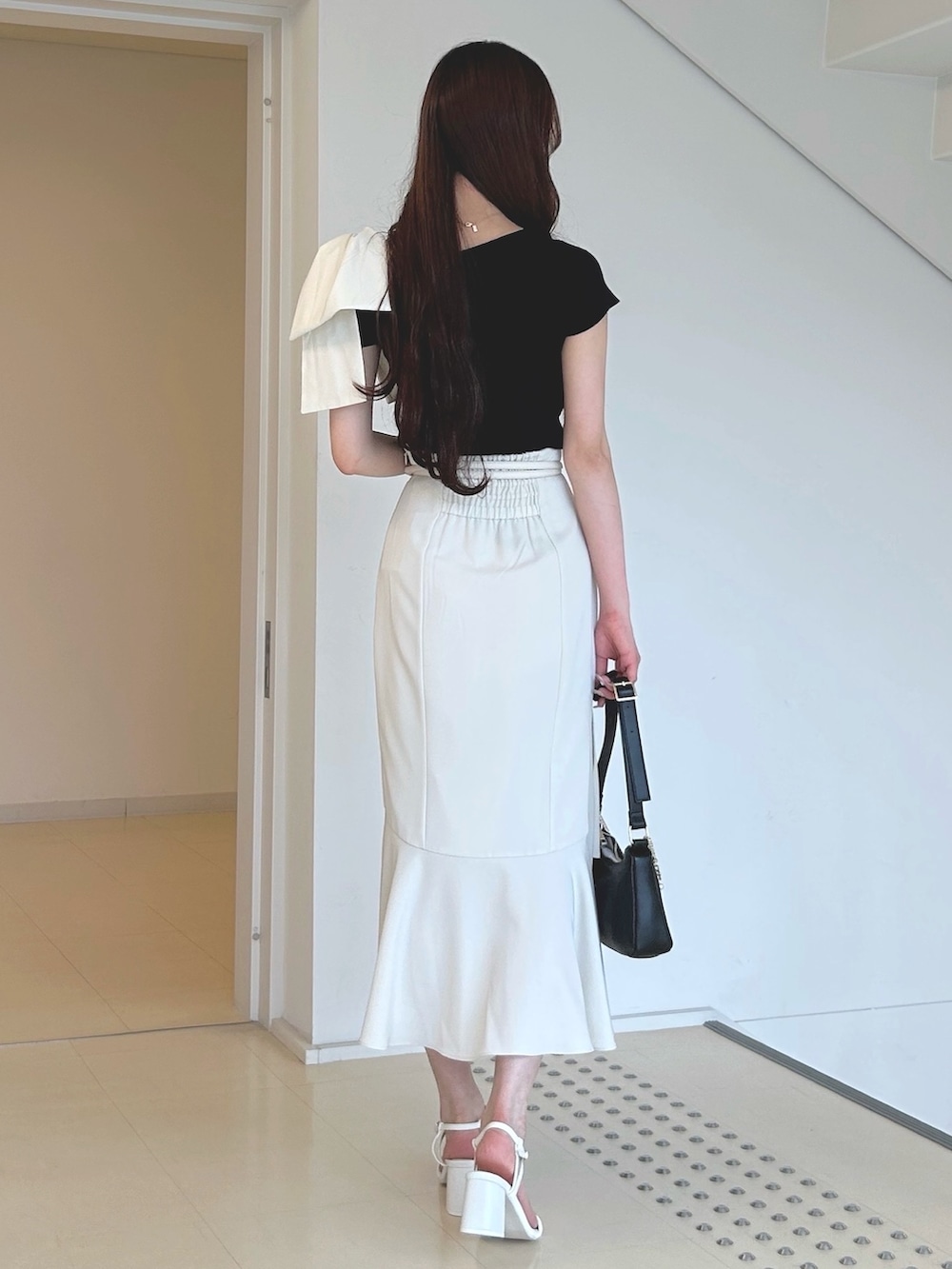 ブラック系のニット/セーター、ブラック系のハンドバッグ、ホワイト系のサンダルを着用したレディースの夏コーディネートの4枚目の写真