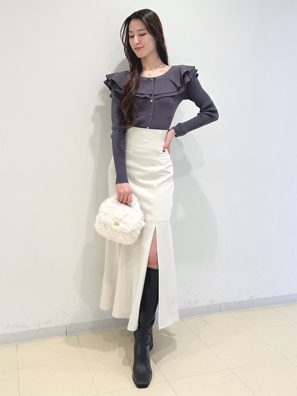 ホワイト系のスカート、ブラック系のブーツ、グレー系のニット/セーターを着用したレディースの冬コーディネートの3枚目の写真